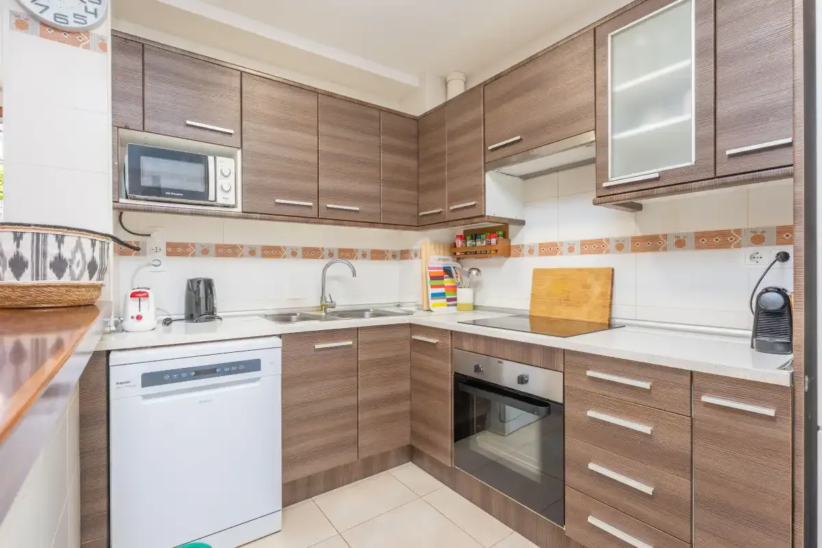 Cocina equipada con armarios en tonos de madera, microondas y horno.