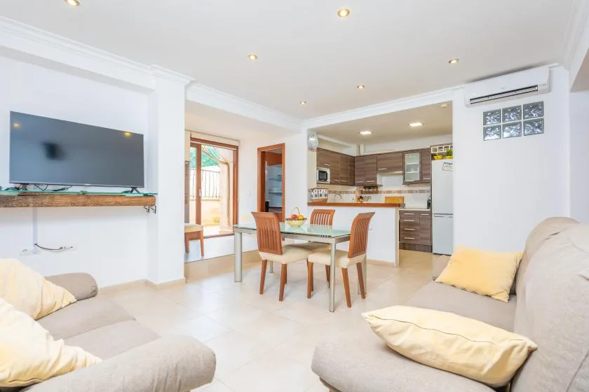 Una luminosa sala-comedor da a la cocina, con un televisor en la pared.