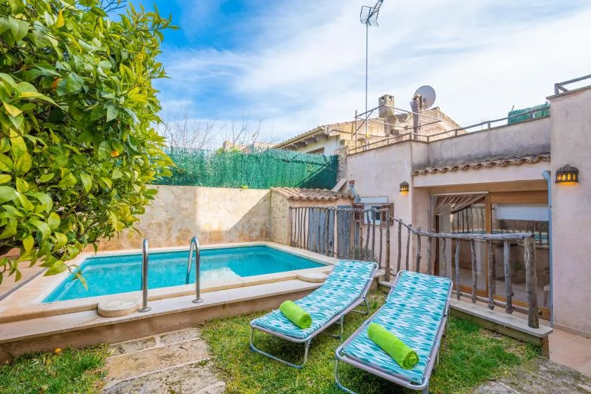 An outdoor pool area with two sun loungers beside a low stone wall.