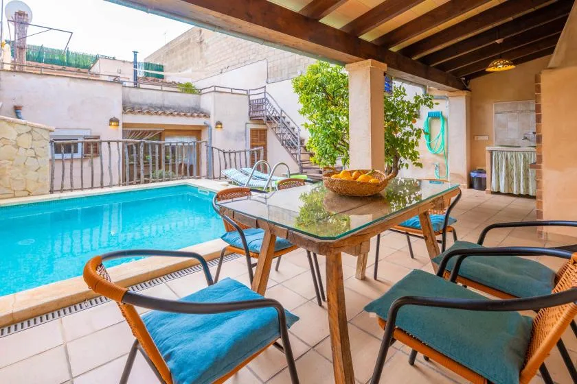 A covered patio with a swimming pool and outdoor dining table.