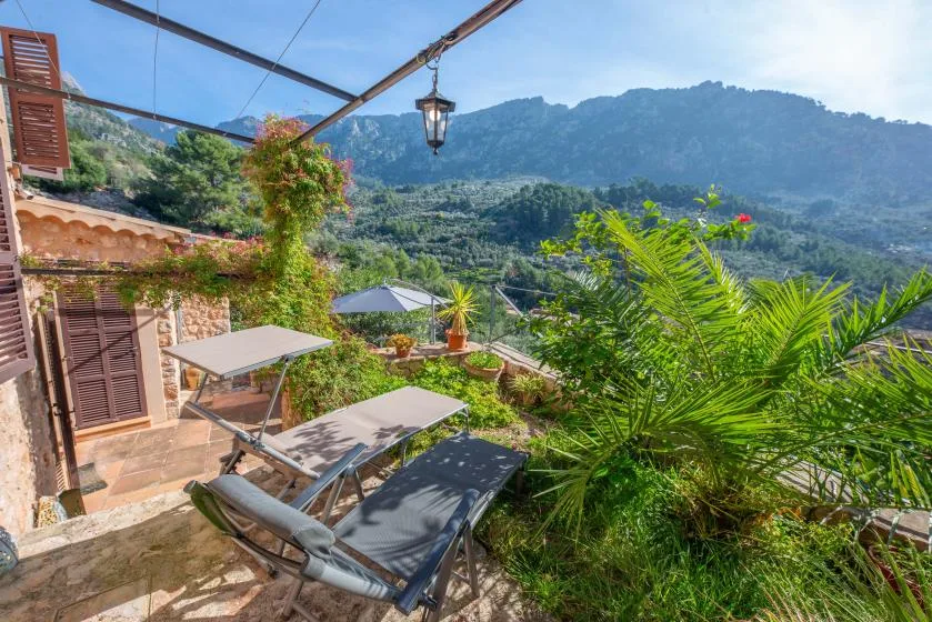 An outdoor terrace with seating overlooks a green mountain landscape.