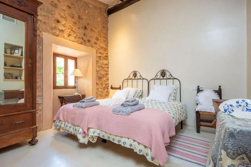 A bedroom with two beds and patterned stone walls.