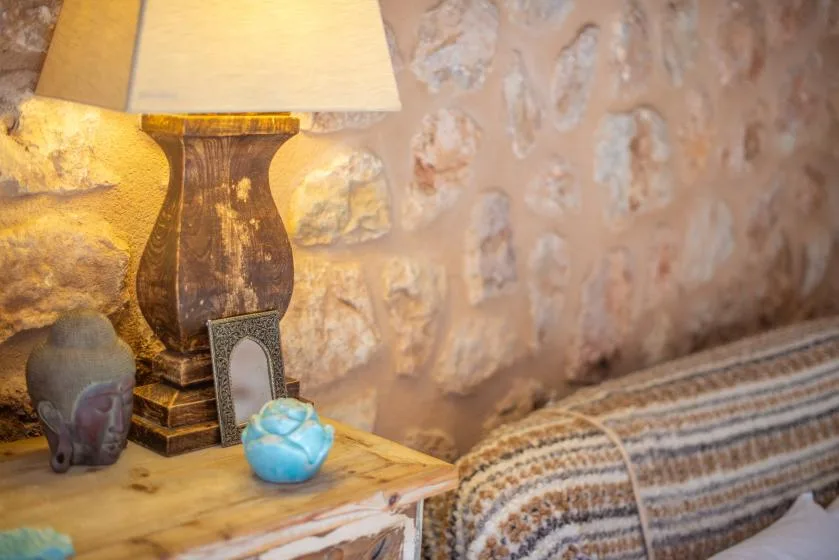 A warmly lit room corner with a table lamp, small decorative objects, and a patterned rug.