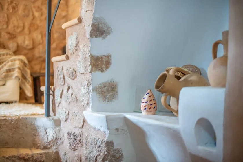 A rustic stone interior with a built-in white shelf displaying pottery.