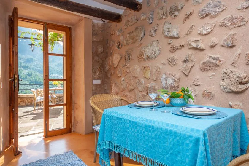 A dining area with a turquoise tablecloth beside an open glass door.