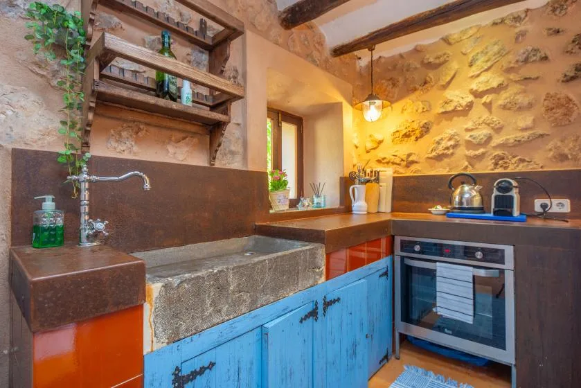 A rustic kitchen with blue cabinets, a stone sink, and a built-in oven.