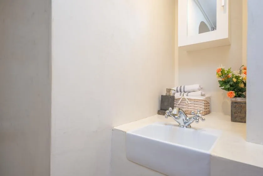 A bathroom vanity with a white sink, folded towels, and flowers.