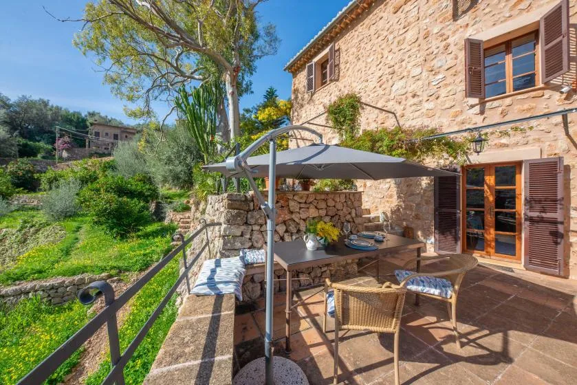 A stone house patio with outdoor seating and a shaded dining area.