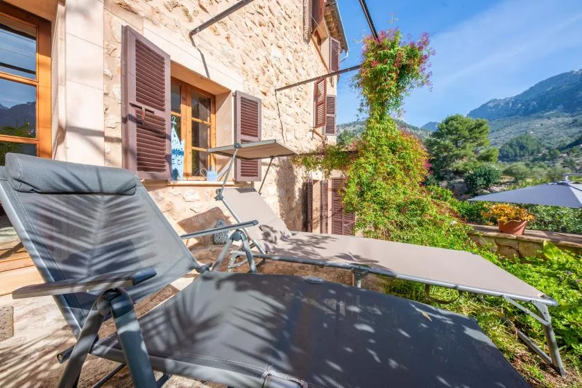 An outdoor terrace with reclining seating overlooks a green mountain valley.