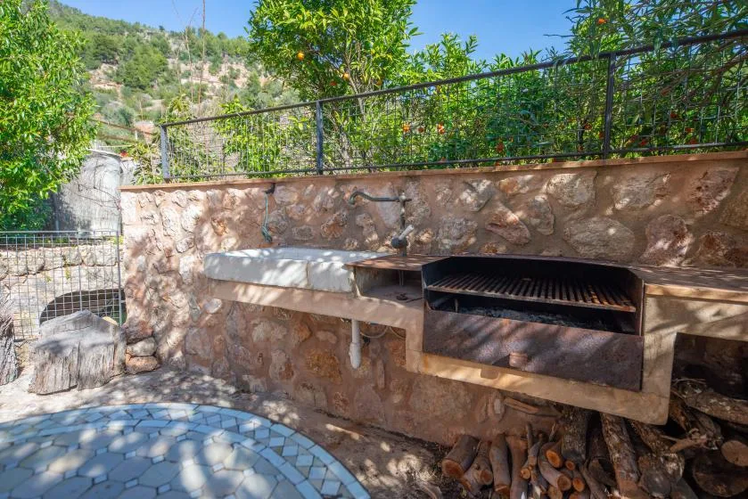 An outdoor stone cooking area with a built-in grill and counter.
