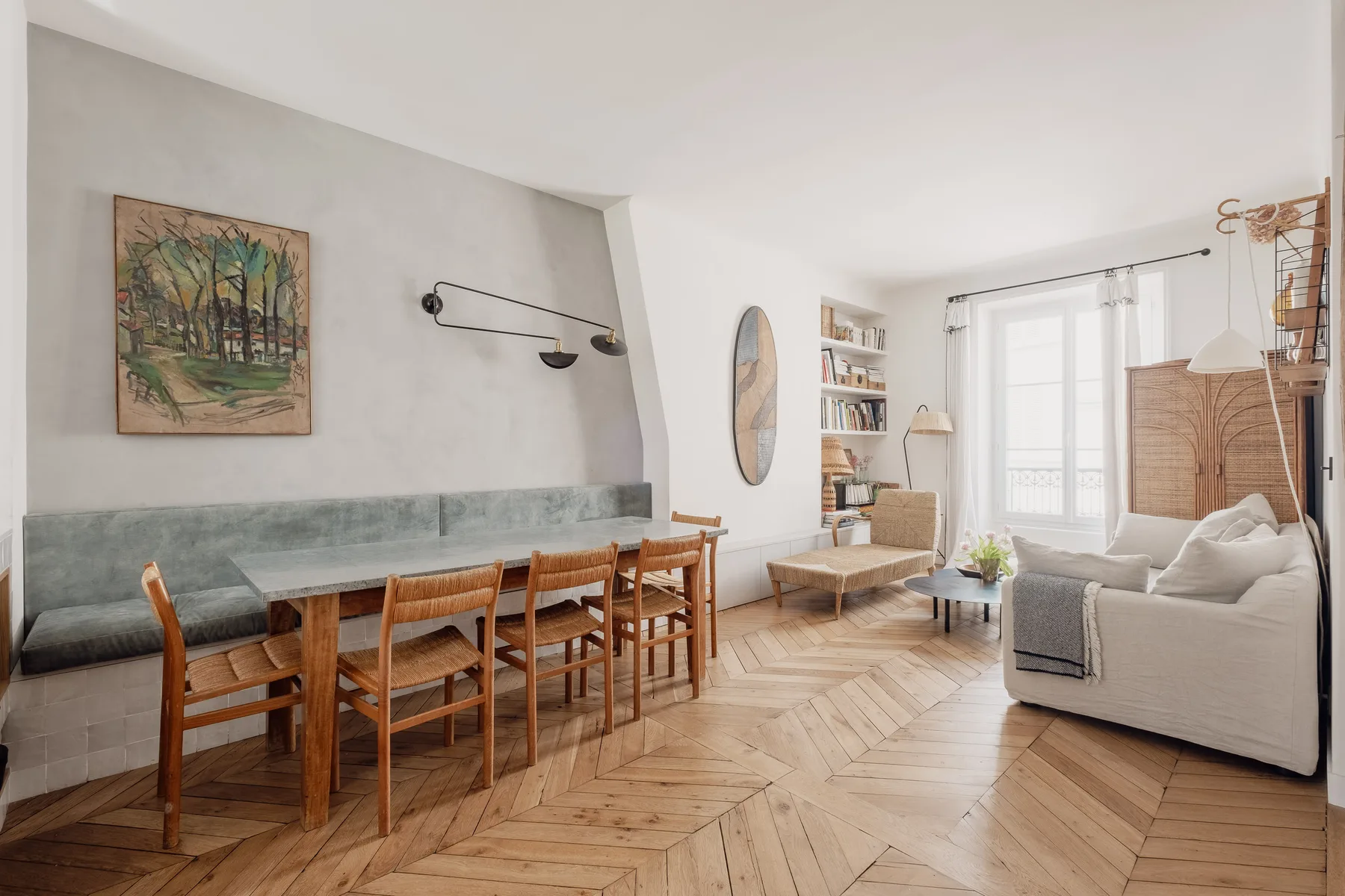 A living and dining area with a long table, seating, and a large window.