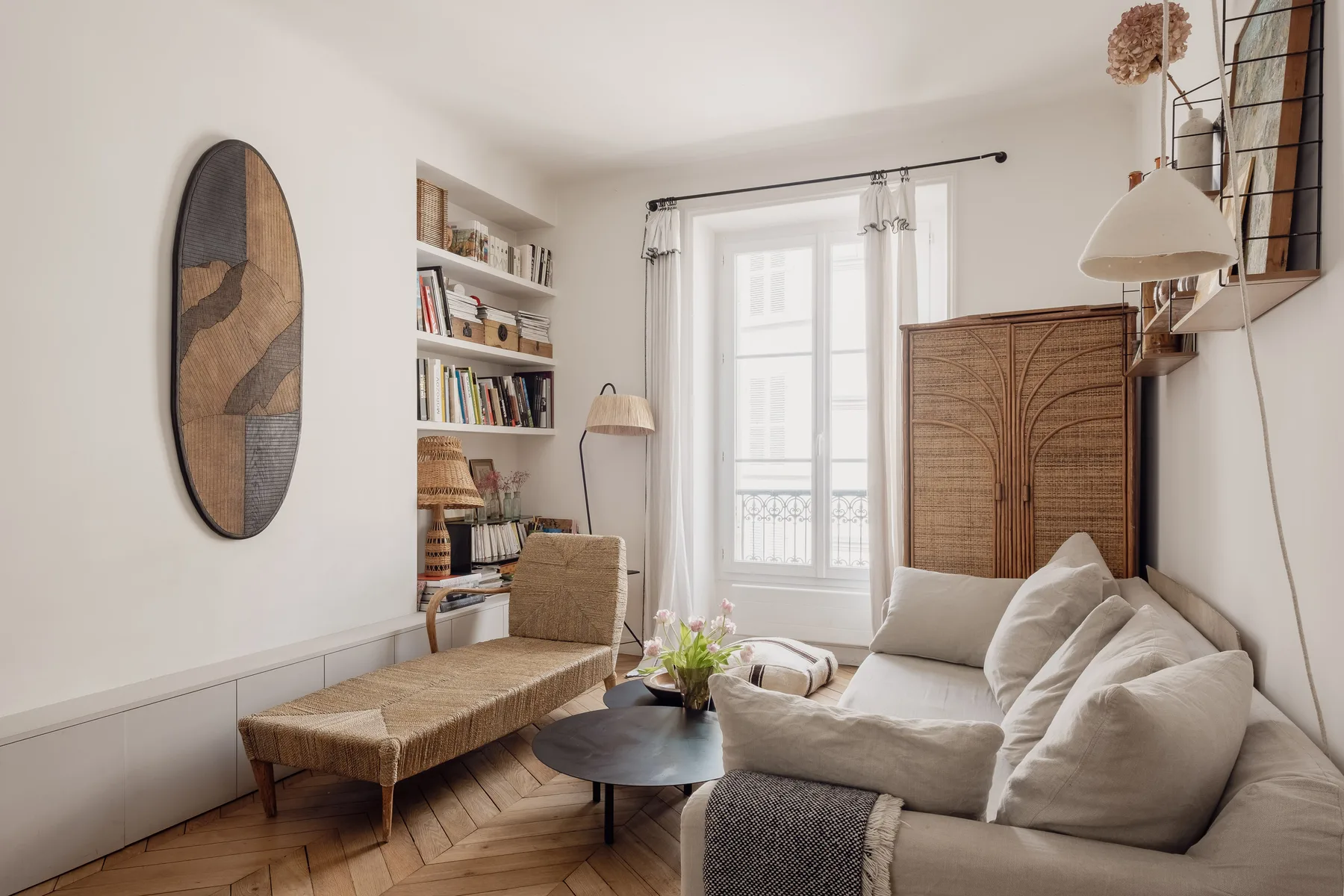 A bright living room with seating, a low table, and a tall window.