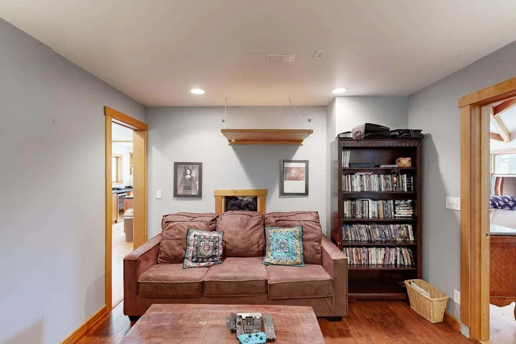 A living room with brown seating, decorative pillows, and a tall bookcase.