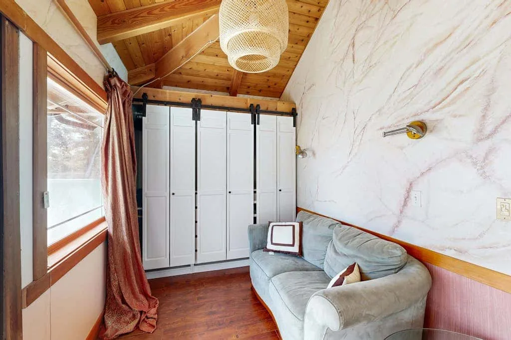 A sitting area with a curved sofa beside a row of white wardrobes.