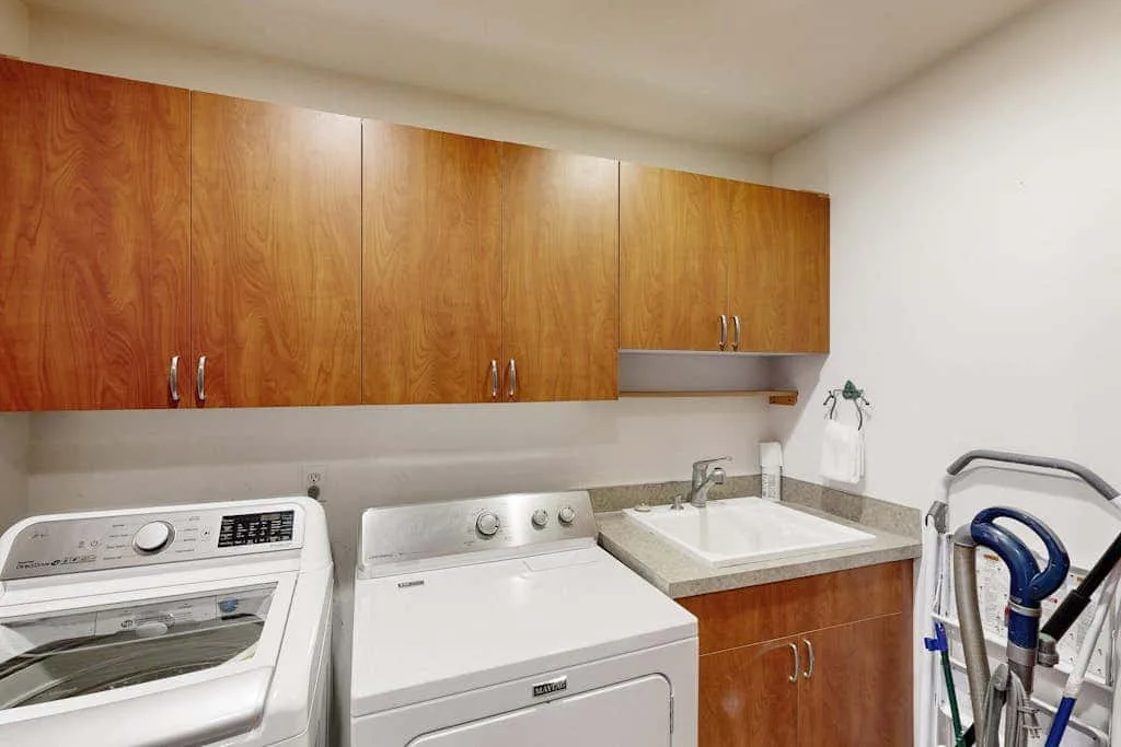 A laundry area with a washing machine, dryer, and countertop beneath wooden cabinets.