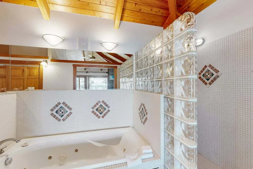A tiled bathroom with a bathtub and a glass-block partition.