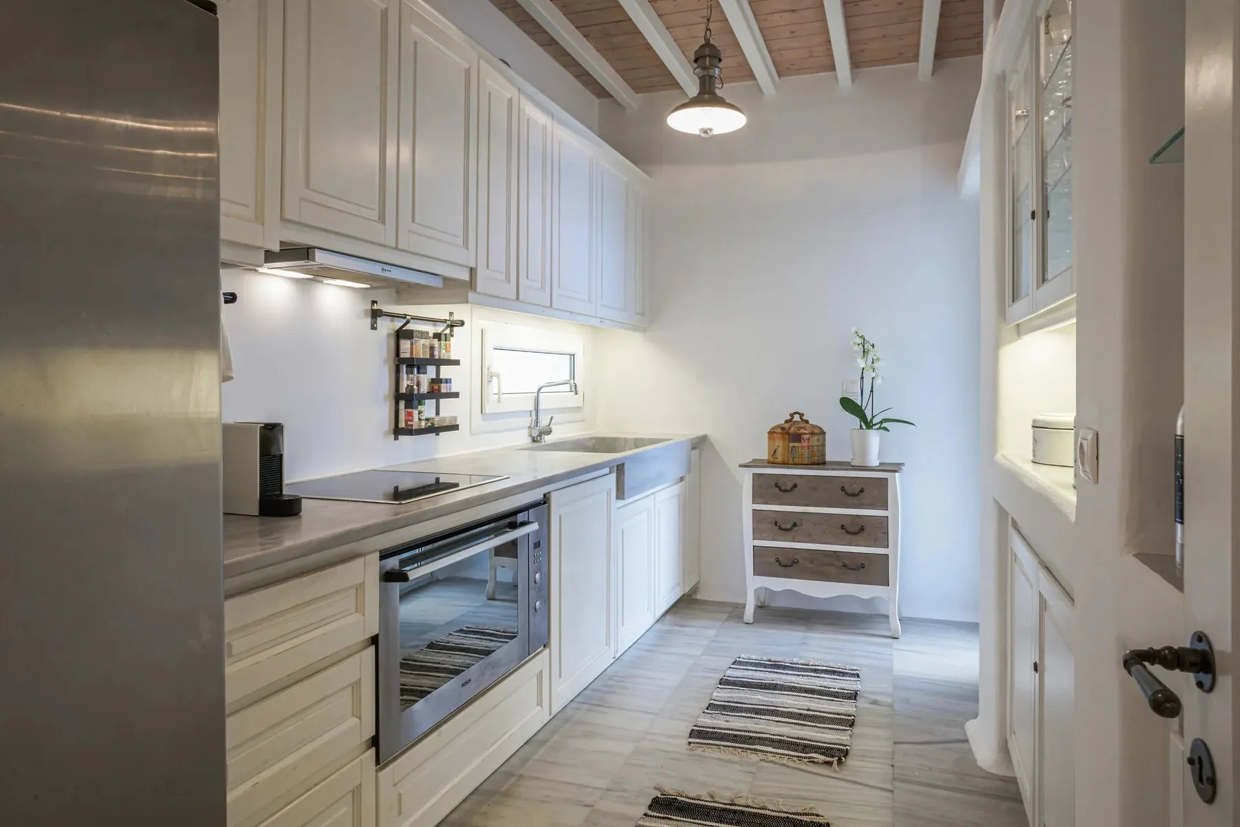 A bright kitchen with white cabinetry, a countertop, and a small dining area.