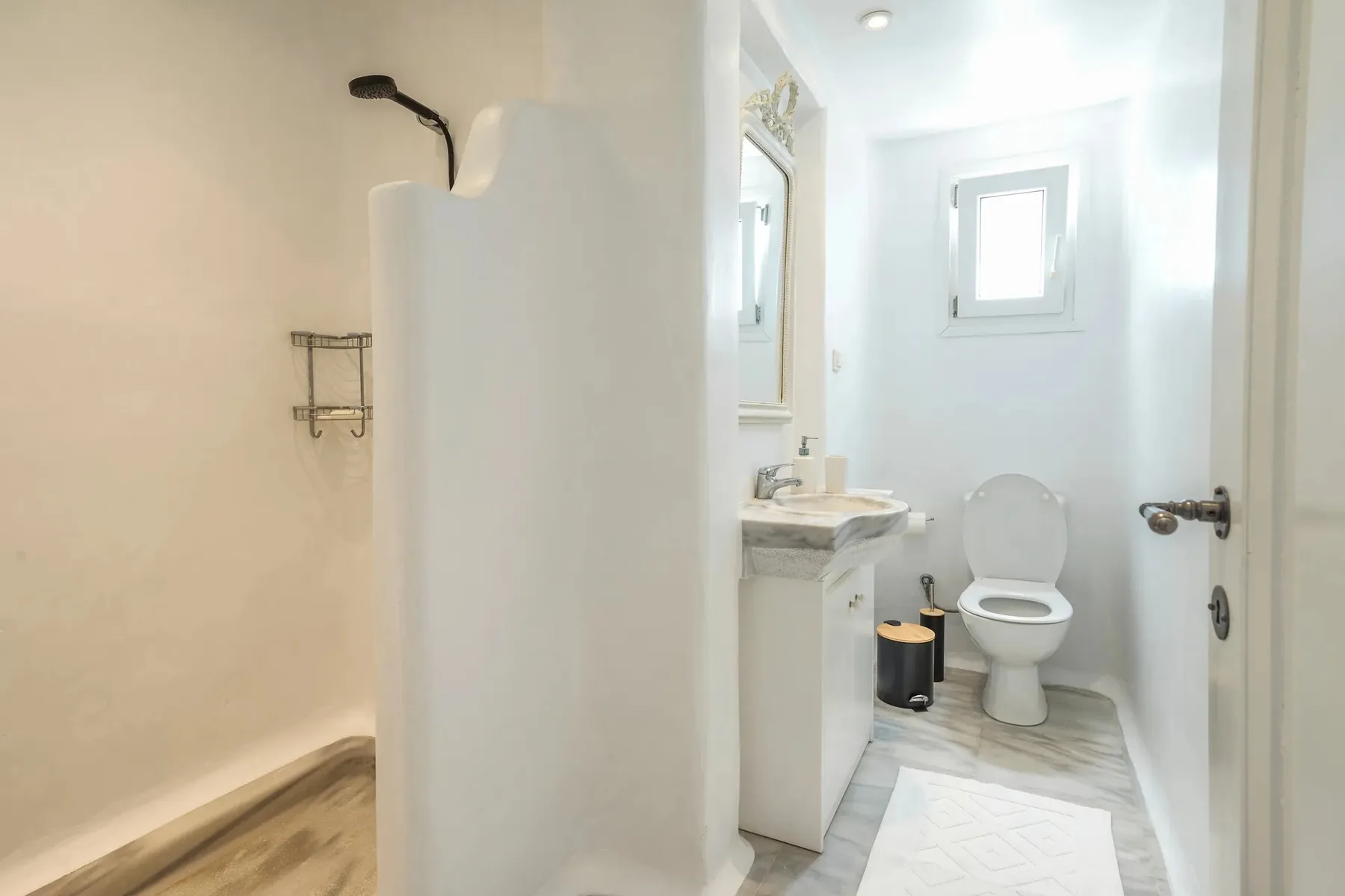 A bright bathroom with a shower, sink, and toilet.