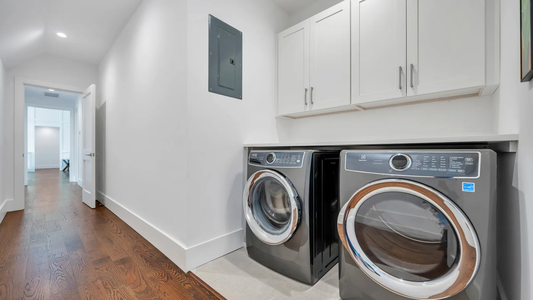 A laundry area with front-loading machines beside a hallway.