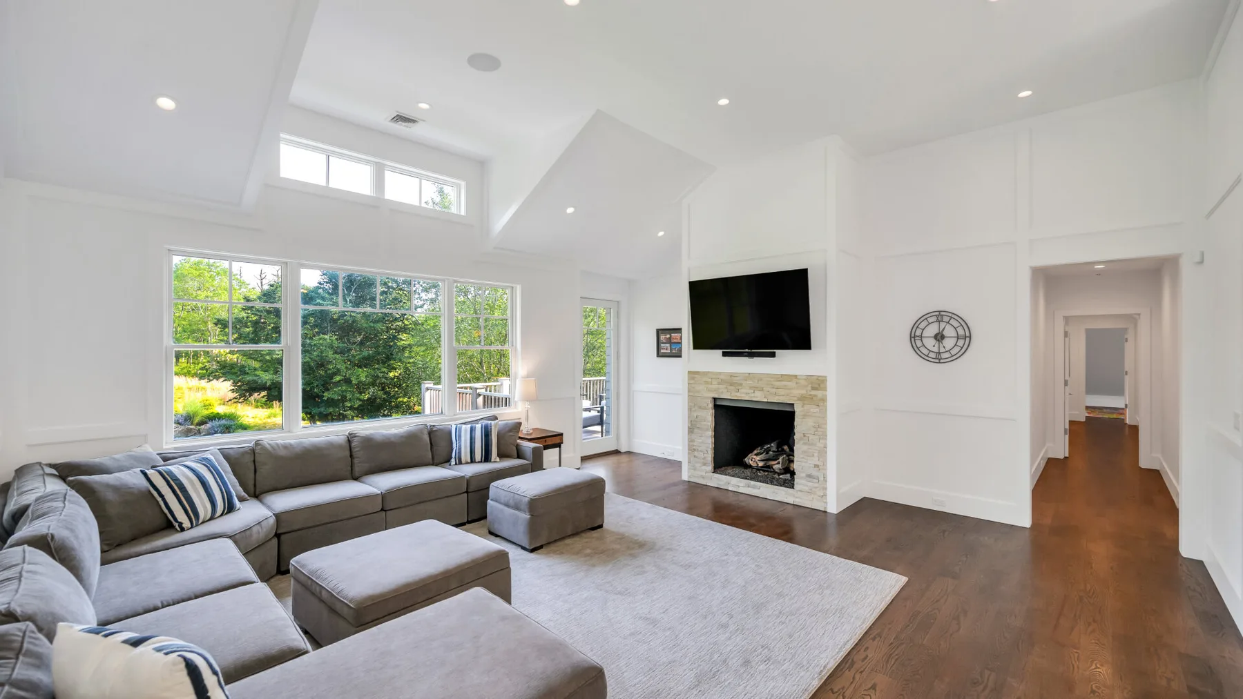 A bright living room with sectional seating, a fireplace, and large windows.