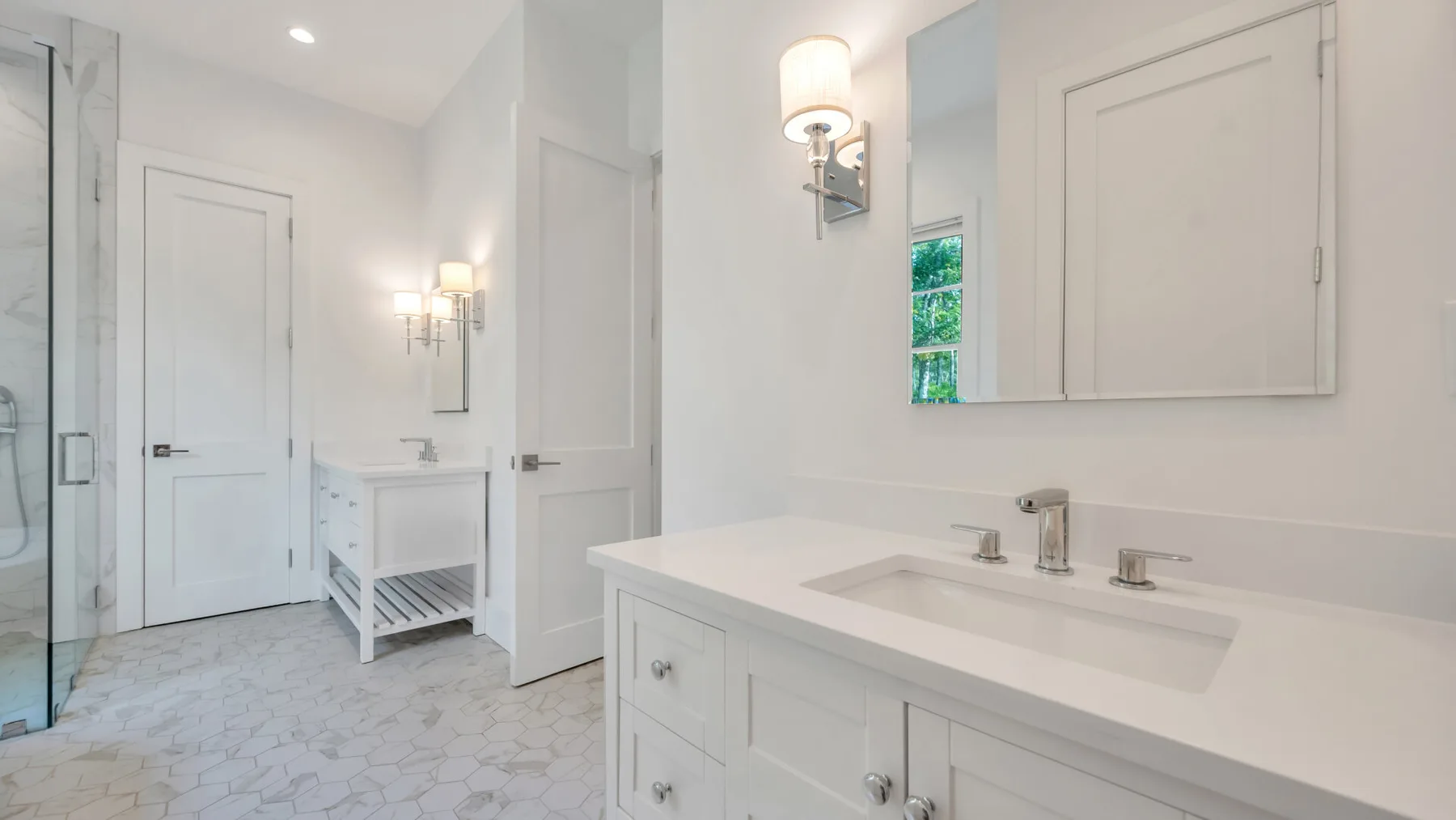 A bright bathroom with a long vanity and a glass shower.