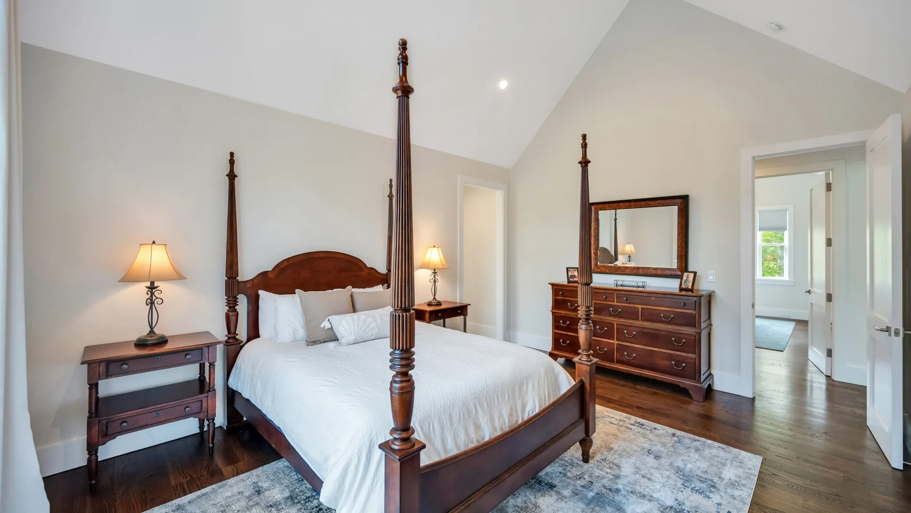 A bedroom with a dark wooden four-poster bed, bedside tables, and a dresser.