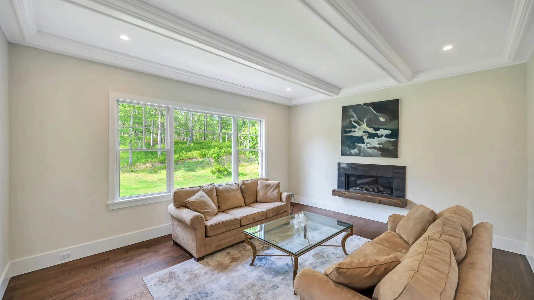 A bright living room with seating, a glass coffee table, and a fireplace.