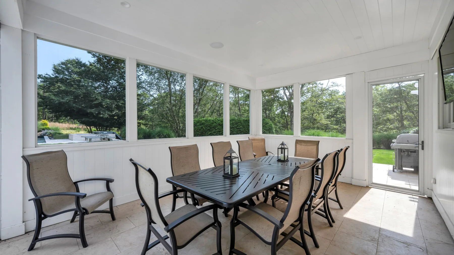 A sunroom dining area with a table and chairs beside large windows.
