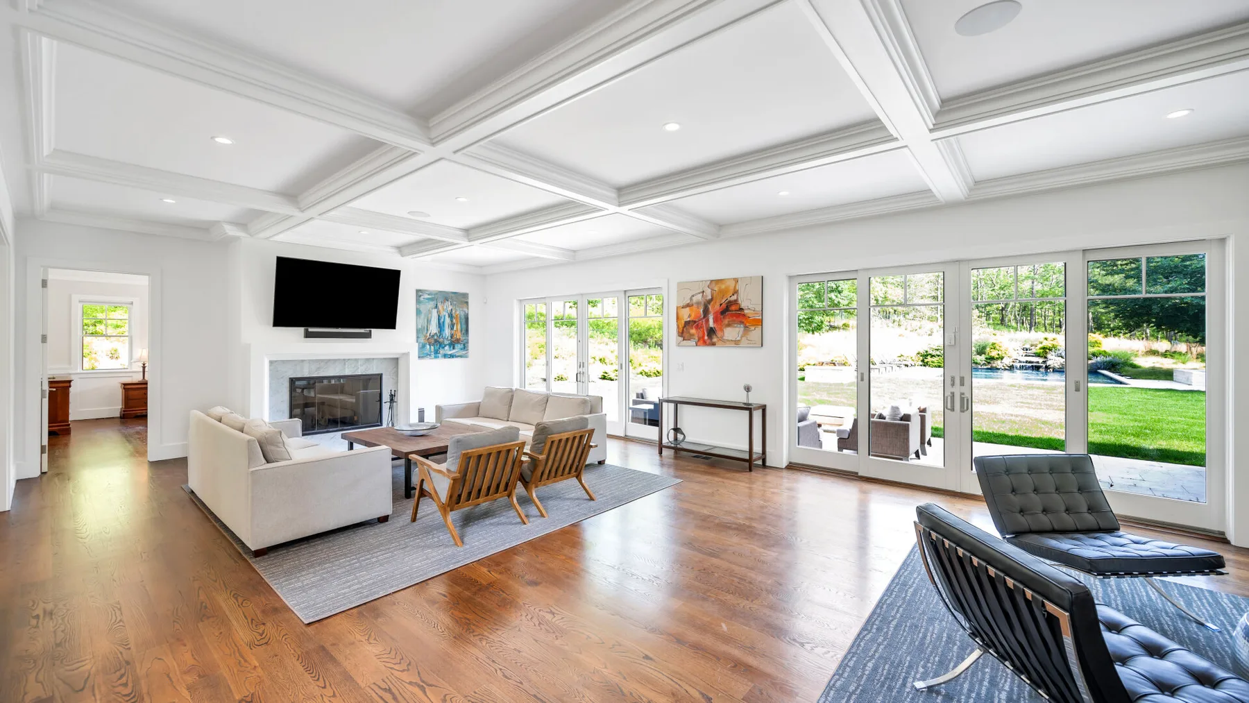A bright living room with a seating area, fireplace, and large windows.