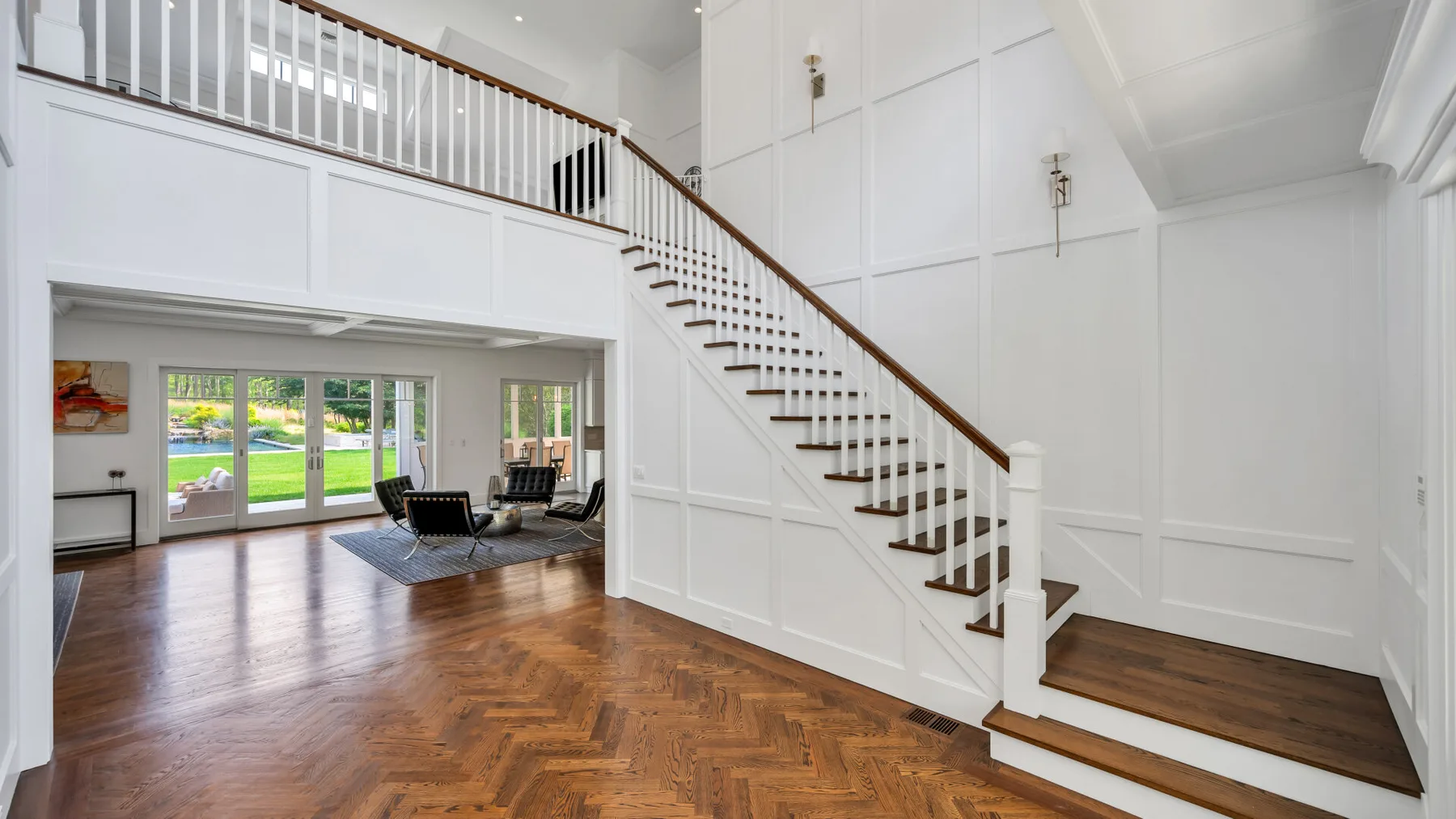 A bright open living room with a staircase and wood flooring.