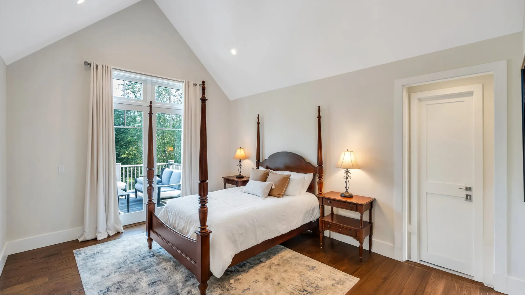 A bedroom with a four-poster bed and glass doors opening onto a patio.