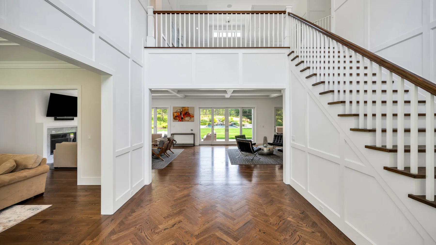 A bright open interior with a wooden staircase leading to an upstairs landing.