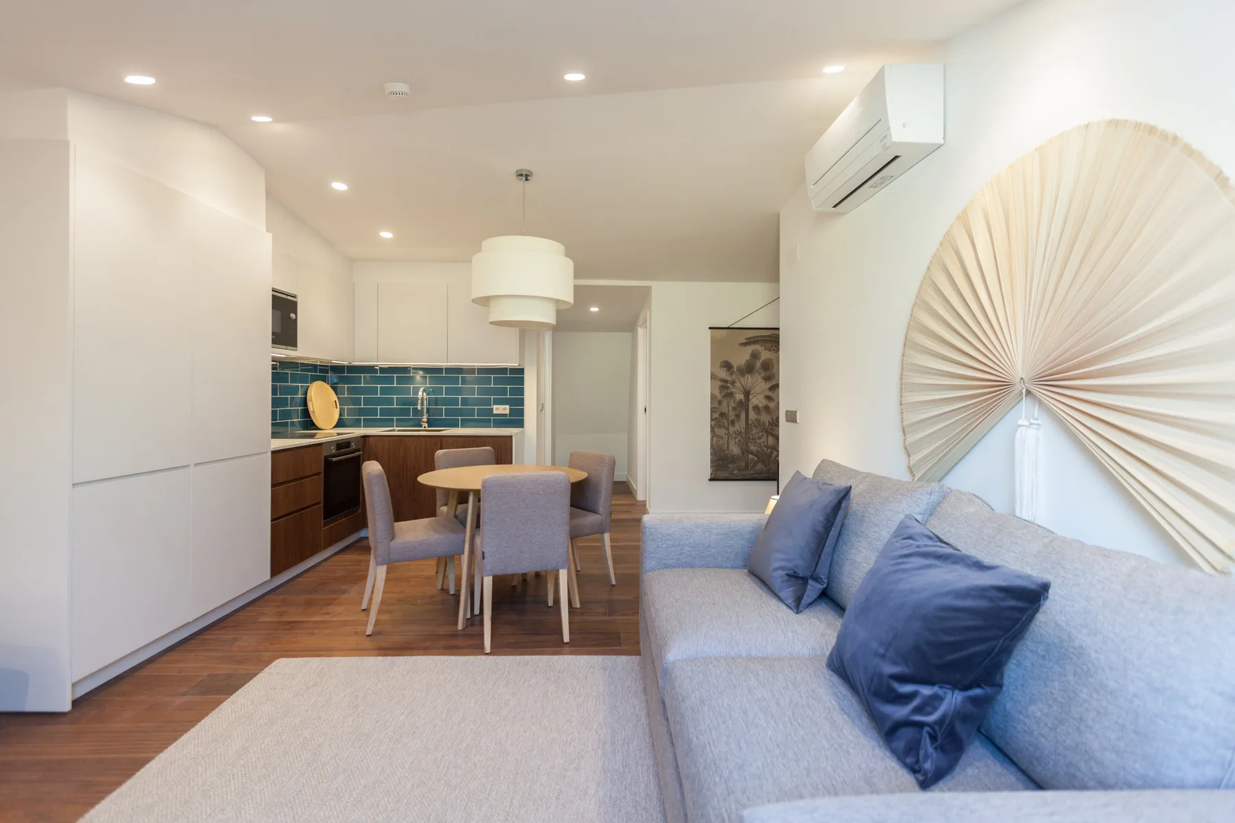 A living and dining area with a sofa beside a compact kitchen.