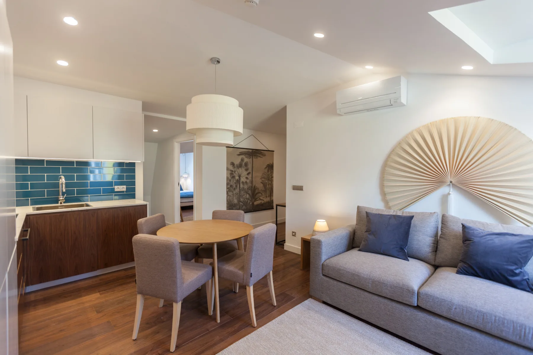 A living and dining area with a gray sofa beside a round table.
