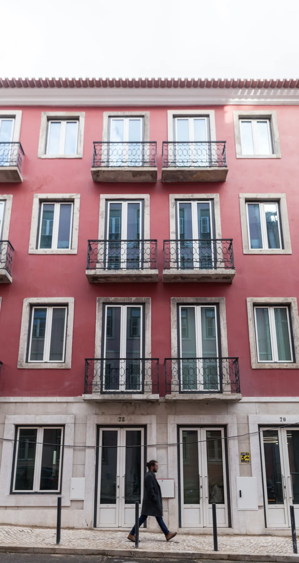 A pink multi-story building with rows of windows and small balconies.