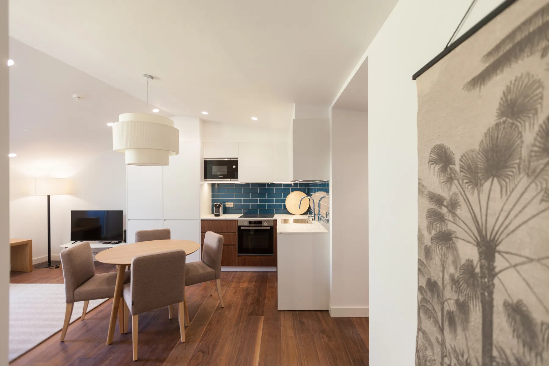 An open-plan living and dining area with a kitchen and blue tile backsplash.