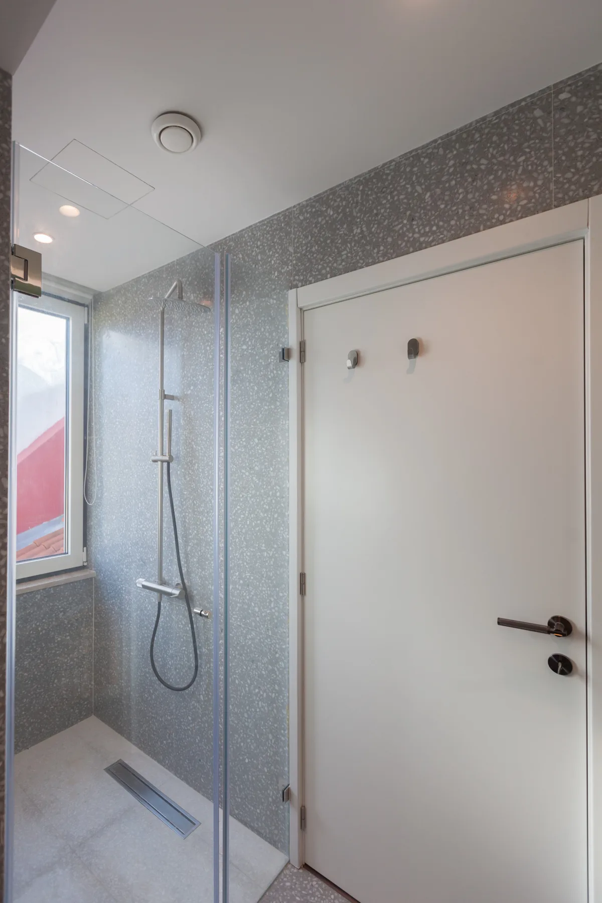 A shower area with gray tiled walls and a glass screen.