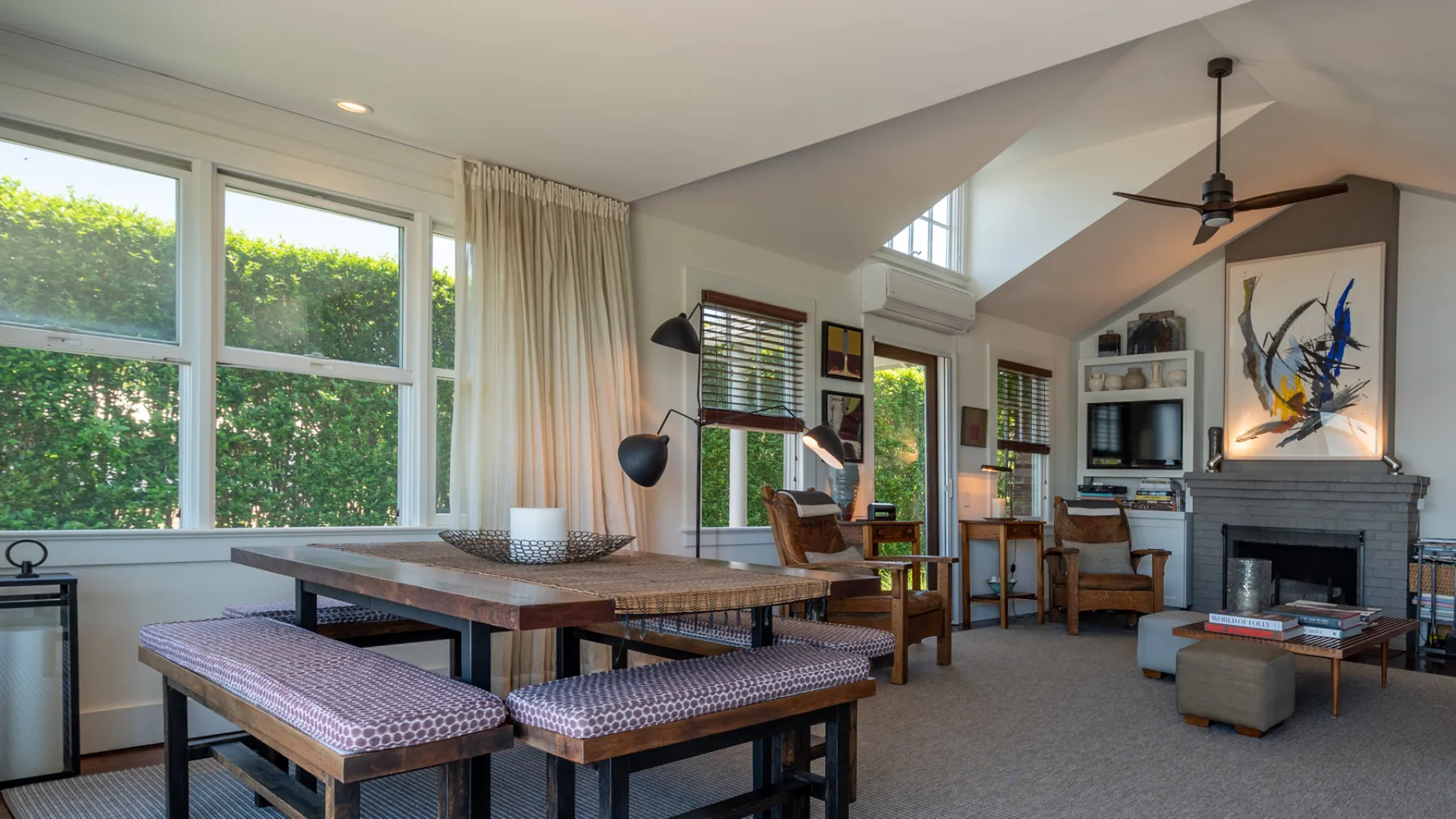 A bright open-plan living and dining room with large windows and a fireplace.