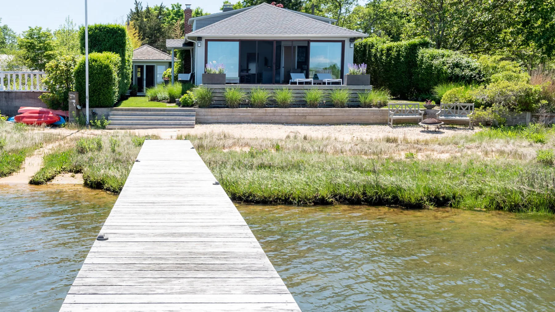 A waterfront house with a long dock extending across the water toward shore.