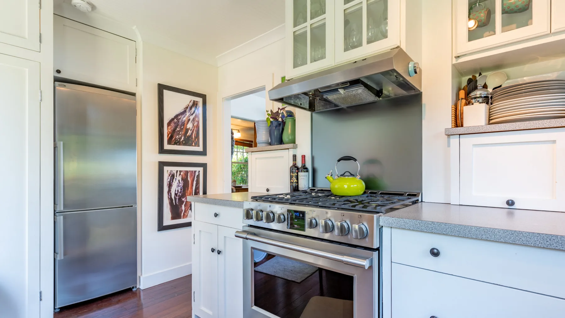 A bright kitchen with a stainless-steel refrigerator and a stove beneath a range hood.