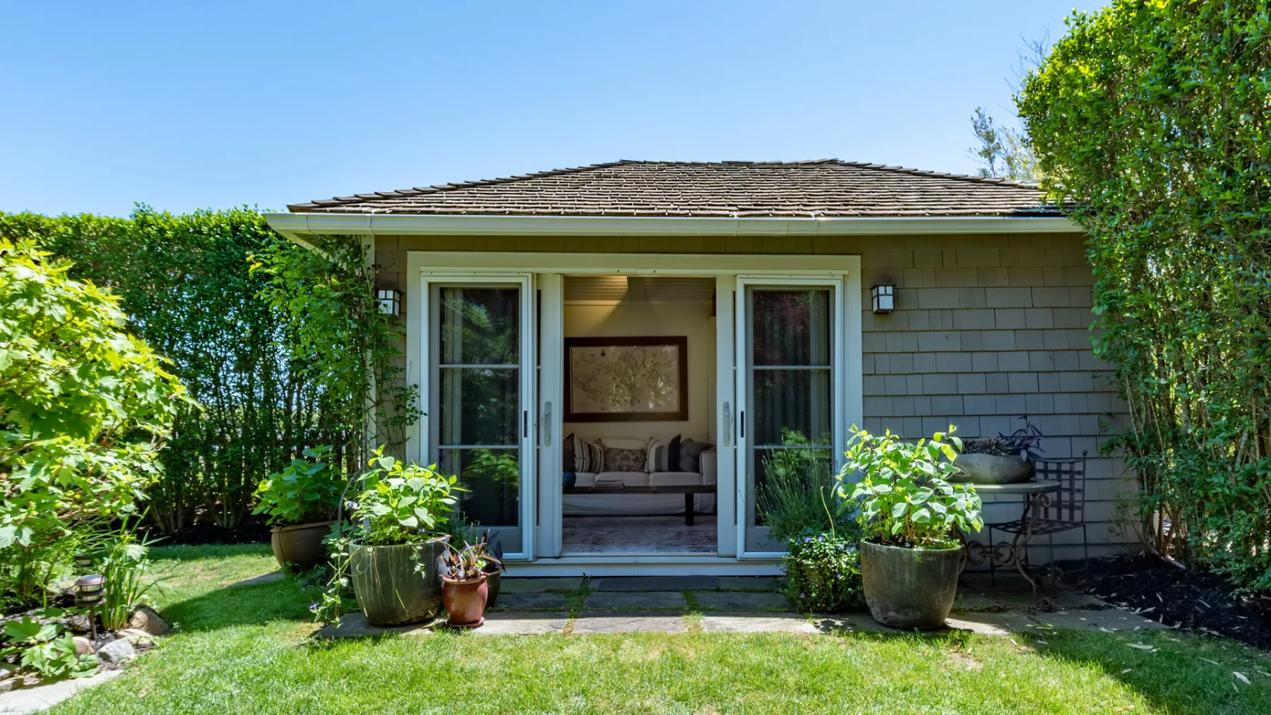 A garden-facing room opens onto a lawn, with potted plants beside the entrance.
