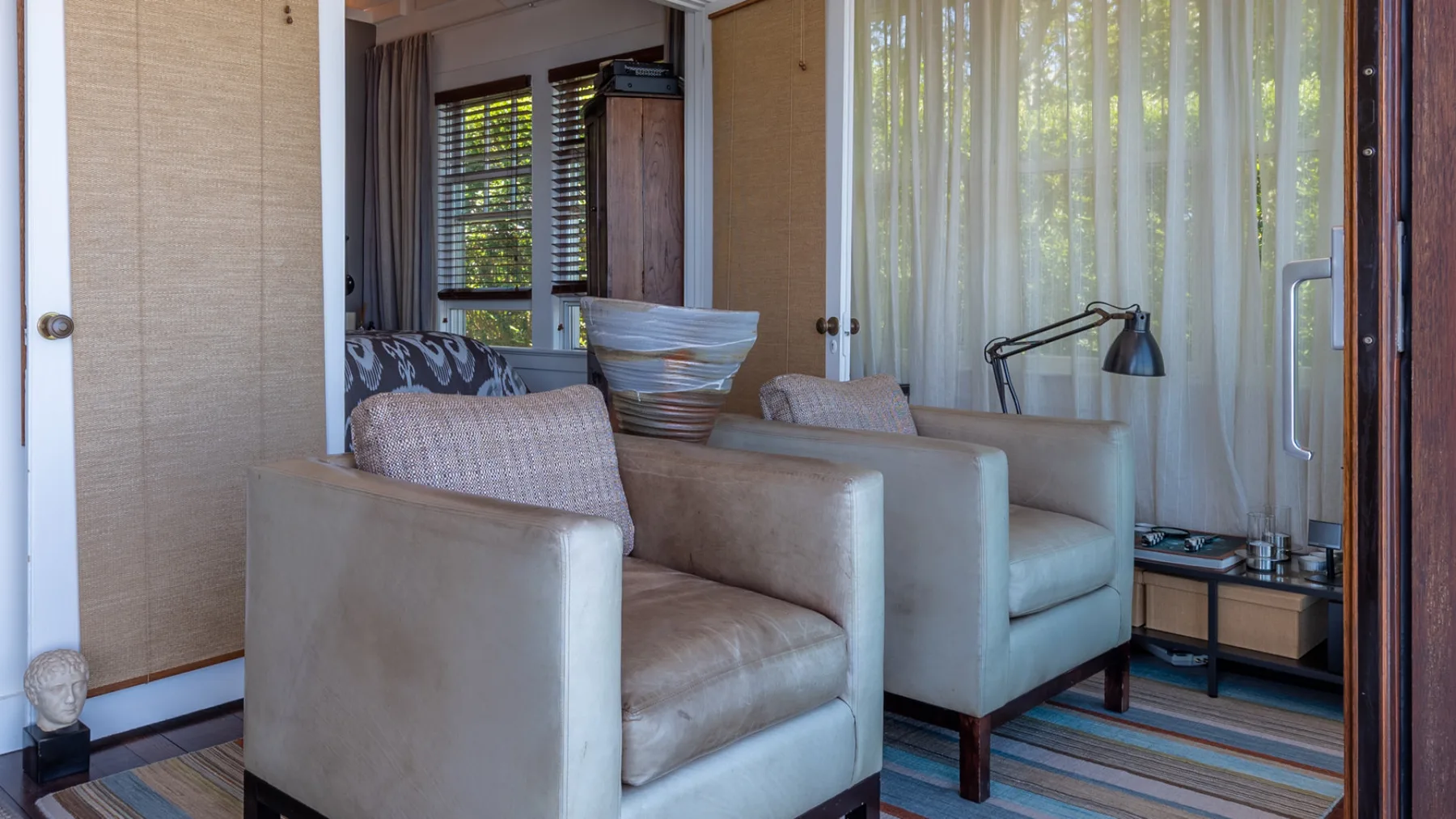 A sitting area with upholstered seating, a floor lamp, and striped flooring.