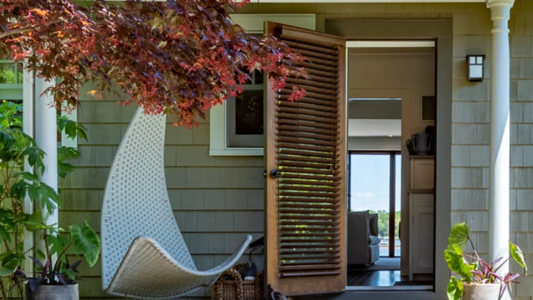 An exterior entry opens onto a bright interior, with a woven lounge chair nearby.