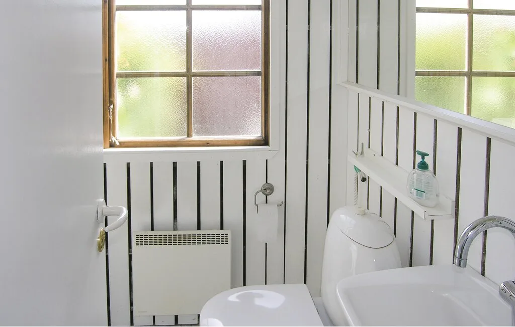 Un baño con inodoro, lavabo y ventanas translúcidas.