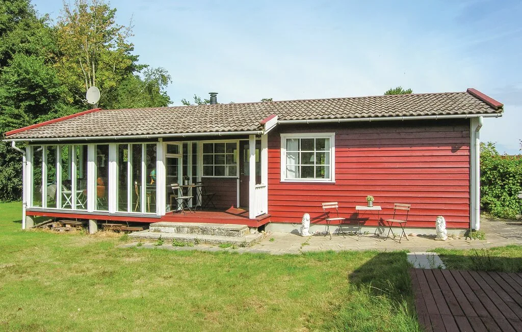 Una casa roja con un porche acristalado cerrado y un jardín con césped.