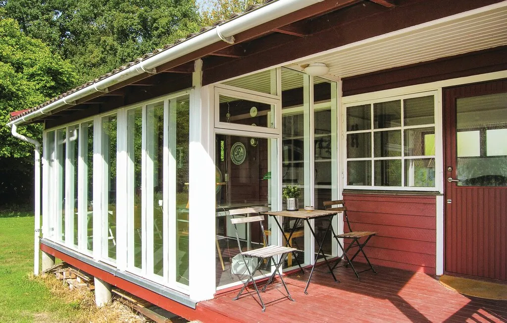Un patio cerrado con vidrio, una mesa pequeña y asientos al aire libre.