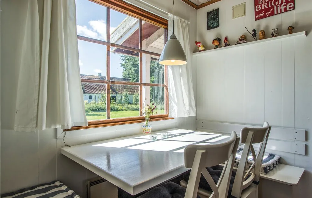 Un comedor luminoso tiene una mesa blanca junto a una ventana grande.