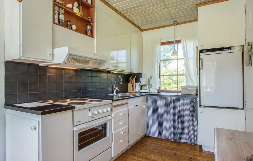 Una cocina con gabinetes blancos, una estufa y una ventana sobre el fregadero.
