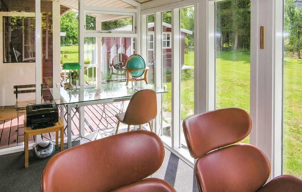 Un luminoso invernadero con asientos de cuero y grandes ventanas con vistas a un jardín.