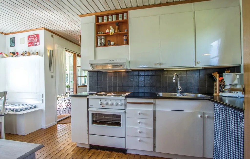 Una cocina compacta con gabinetes blancos, una estufa y un fregadero junto a la encimera.